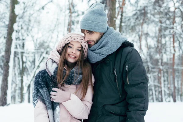 Joven hombre abrazando novia en invierno bosque - foto de stock