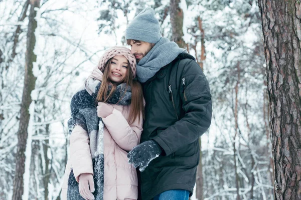 Young man hugging girlfriend in winter forest — Stock Photo