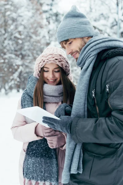 Portrait de jeune couple heureux avec tablette dans un parc enneigé — Photo de stock