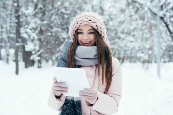 Retrato de la joven sonriente con la tableta en el parque de invierno - foto de stock