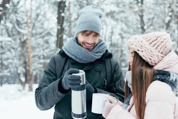 Jovem casal beber chá de garrafa térmica no parque de inverno — Fotografia de Stock