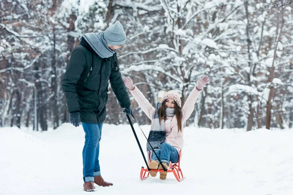 Young couple sledging together on winter day in park — Stock Photo