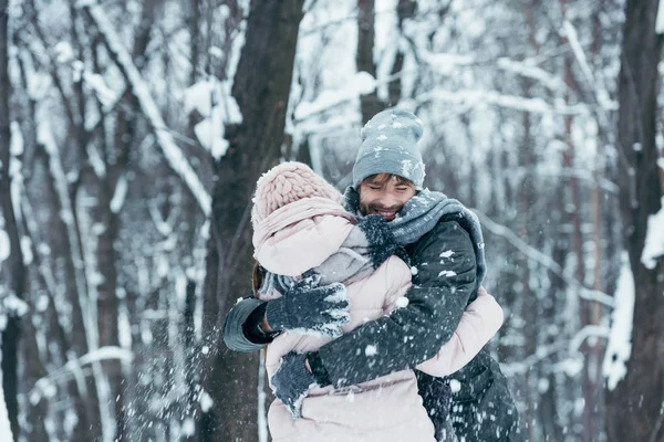 Jovem abraçando namorada na floresta de inverno — Fotografia de Stock