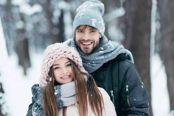 Портрет счастливой пары, смотрящей в камеру в снежном парке — стоковое фото