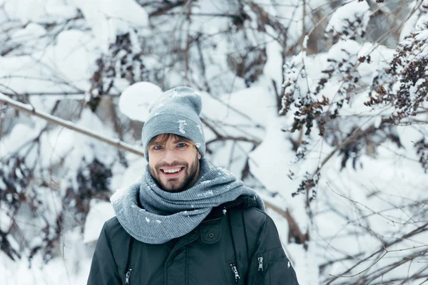 Porträt eines fröhlichen jungen Mannes, der an einem Wintertag im Park in die Kamera blickt — Stockfoto