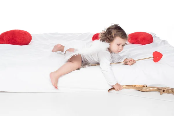 Маленький ангел на ліжку з луком і стрілою, ізольований на білому — стокове фото