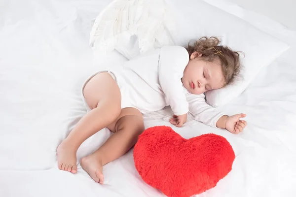 Маленька дитина зі сном на ліжку з серцем, ізольована на білому — стокове фото