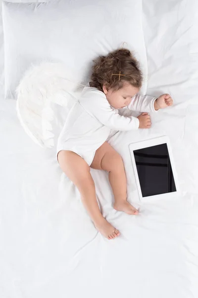 Малыш спит на кровати с цифровым столом — стоковое фото