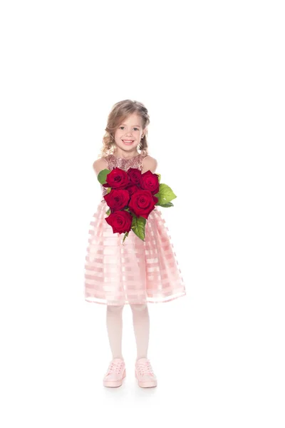 Adorable niño en vestido sosteniendo ramo de rosas rojas, aislado en blanco - foto de stock