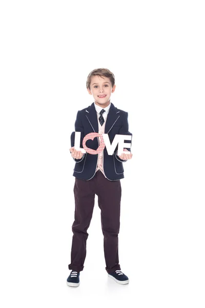 Bonito menino segurando palavra amor e sorrindo para a câmera isolado no branco — Fotografia de Stock