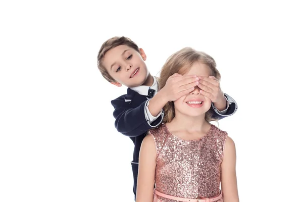 Cute smiling little boy closing eyes to adorable happy little girl isolated on white — Stock Photo