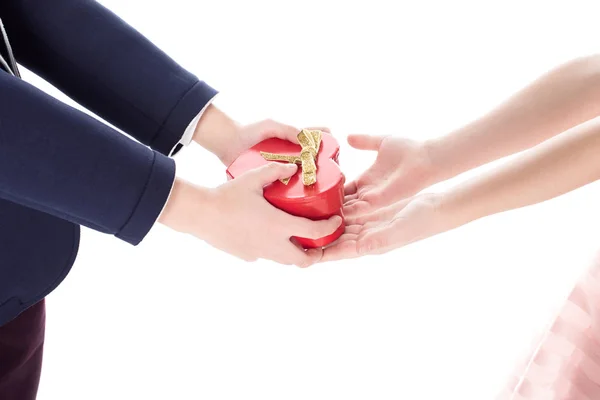 Abgeschnittene Aufnahme eines Jungen im Anzug, der einem kleinen Mädchen eine herzförmige Geschenkschachtel auf weißem Grund präsentiert — Stockfoto