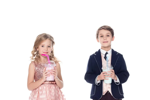 Adorables petits enfants tenant milkshakes dans des tasses en plastique et souriant à la caméra isolée sur blanc — Photo de stock