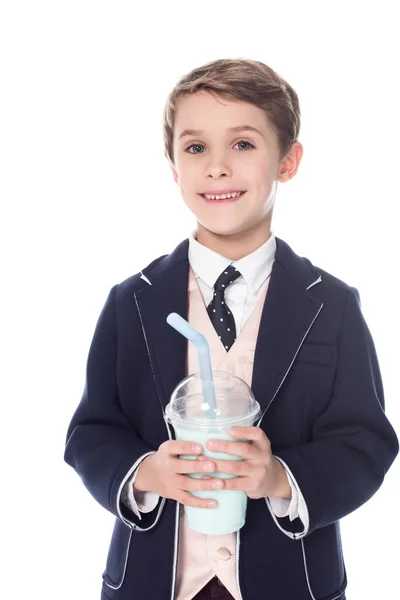 Süßer kleiner Junge hält Milchshake im Plastikbecher und lächelt in die Kamera isoliert auf weiß — Stockfoto