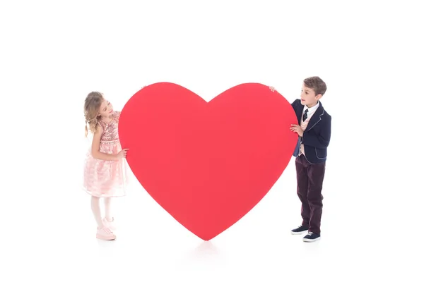 Чарівні маленькі діти тримають великий червоний символ серця ізольовані на білому — стокове фото