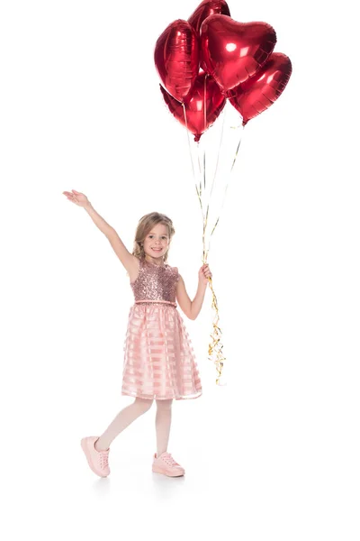 Bellissimo bambino in abito rosa con palloncini a forma di cuore e sorridente alla fotocamera isolata su bianco — Foto stock