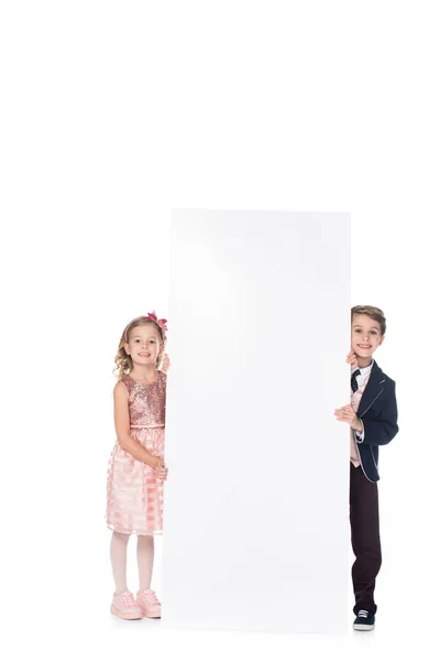 Чарівні усміхнені діти тримають порожній банер і посміхаються на камеру ізольовані на білому — стокове фото