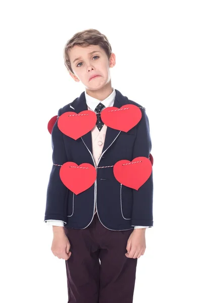 Aufgeregter kleiner Junge im Anzug, der mit Seil und roten Herzen gebunden bleibt und isoliert auf weiße Kamera blickt — Stockfoto