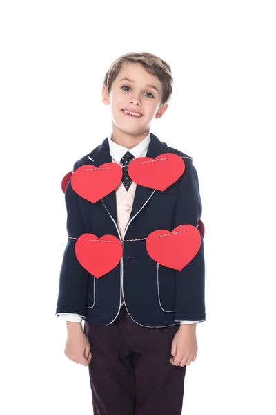 Lindo niño en traje permaneciendo atado con cuerda y corazones rojos, sonriendo a la cámara aislada en blanco - foto de stock