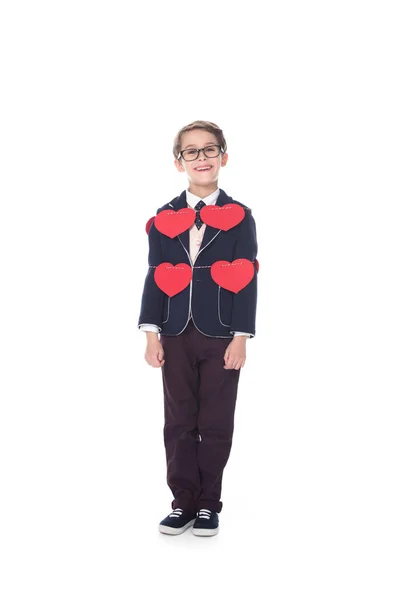 Lindo niño sonriente en traje y gafas permaneciendo atado con cuerda y corazones rojos aislados en blanco - foto de stock