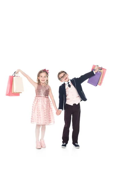 Adorável crianças segurando sacos de compras e sorrindo para a câmera isolada no branco — Fotografia de Stock