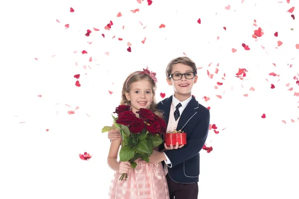 Adorable happy kids with roses and heart shaped gift box hugging and smiling at camera on white — Stock Photo