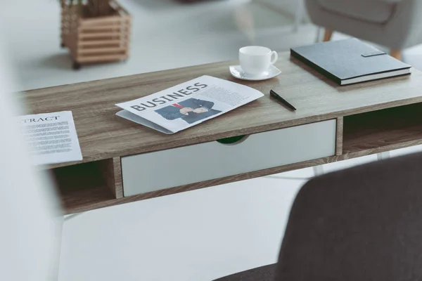 Taza y periódico de negocios en mesa de madera en la oficina - foto de stock