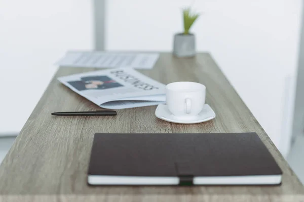 Кубок и ноутбук с ручкой на деревянном столе — стоковое фото