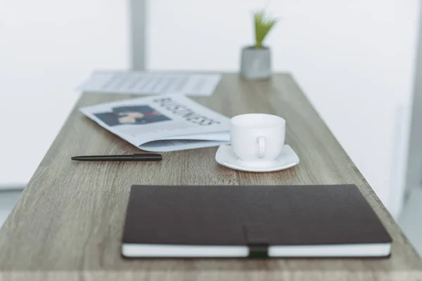 Cup and notebook with pen on wooden table — Stock Photo