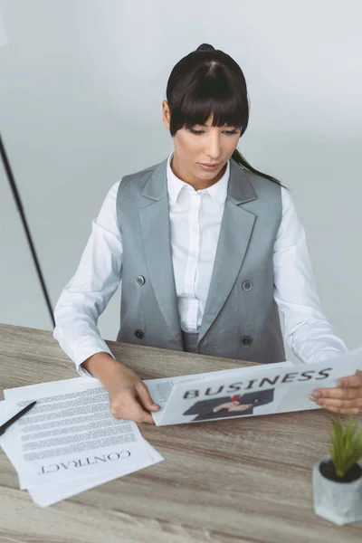 Businesswoman reading newspaper isolated on gray — Stock Photo