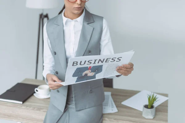 Cropped image of businesswoman reading newspaper isolated on gray — Stock Photo