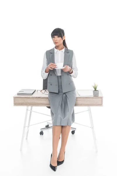 Бізнес-леді стоїть з чашкою кави ізольовані на білому — стокове фото