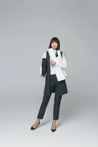 Geschäftsfrau steht mit Aktentasche und Blaupausen auf grau — Stockfoto