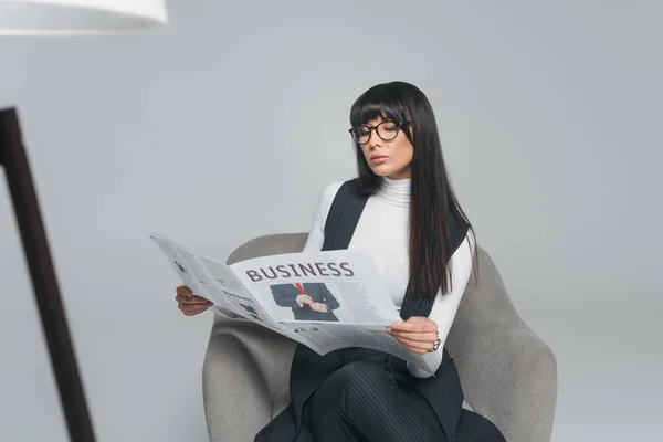 Attractive brunette businesswoman reading newspaper isolated on gray — Stock Photo