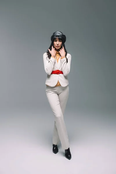 Hermosa mujer morena en traje blanco posando en gris - foto de stock