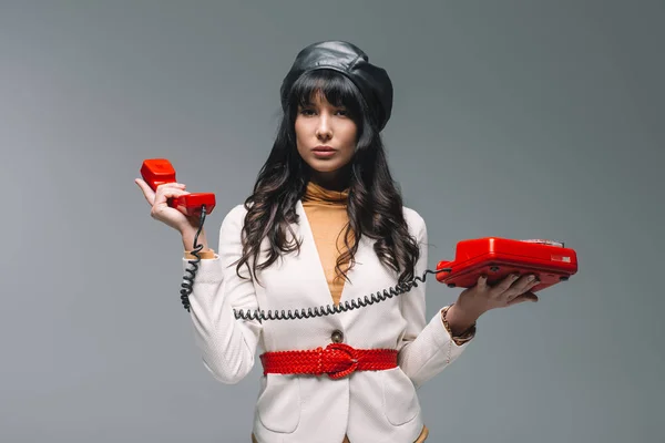 Attractive brunette woman in white suit with red landline phone isolated on gray — Stock Photo