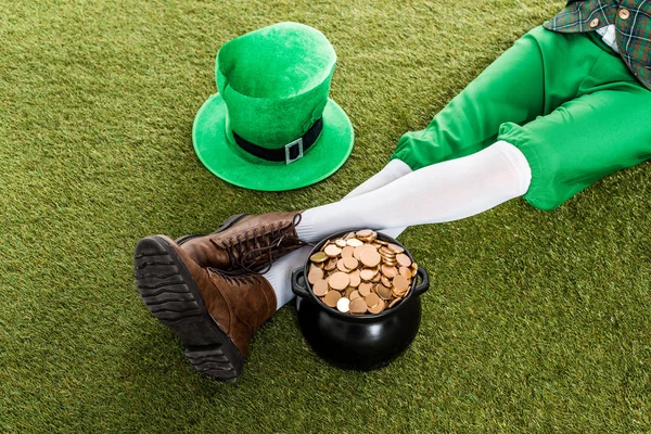 Vue recadrée du lutin avec chapeau et pot d'or assis sur l'herbe verte — Photo de stock