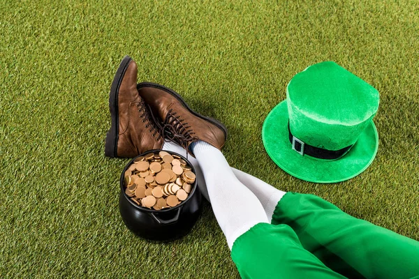Vue recadrée du lutin avec pot d'or et chapeau assis sur l'herbe verte — Photo de stock