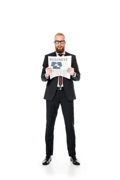 Bearded young businessman in eyeglasses holding newspaper and looking at camera isolated on white — Stock Photo