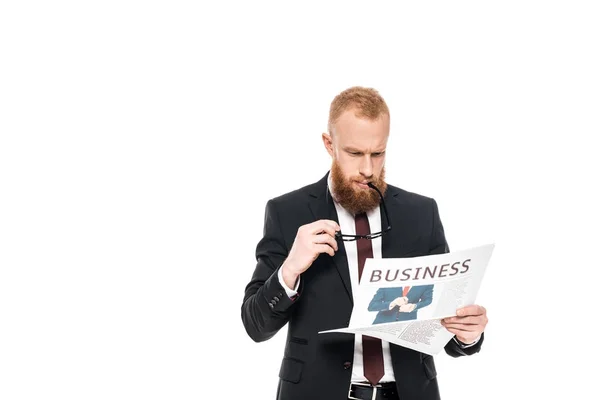 Serious bearded businessman holding eyeglasses and reading newspaper isolated on white — Stock Photo
