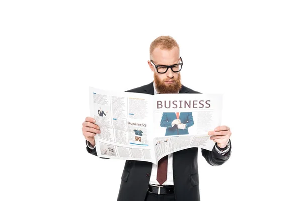 Ernster junger bärtiger Geschäftsmann mit Brille liest Zeitung isoliert auf weißem Grund — Stockfoto