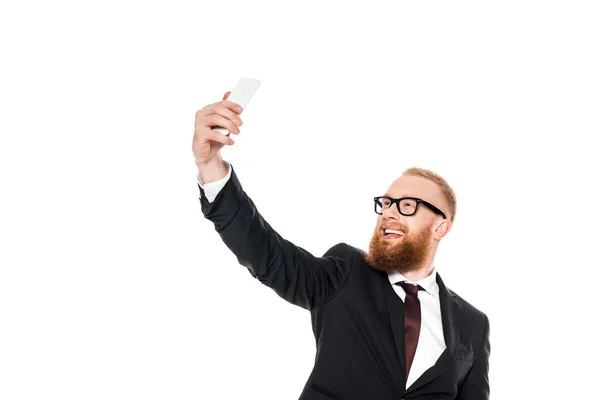 Cheerful young businessman in eyeglasses taking selfie with smartphone isolated on white — Stock Photo