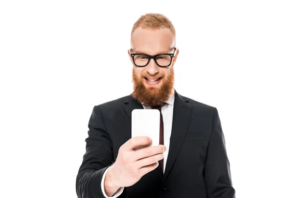 Jeune homme d'affaires souriant dans les lunettes en utilisant smartphone isolé sur blanc — Photo de stock