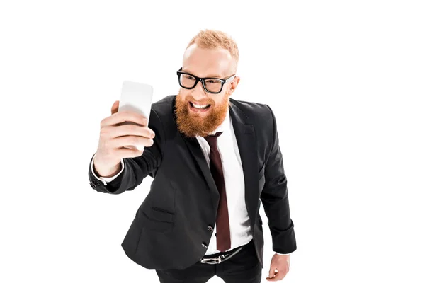 Vue grand angle de jeune homme d'affaires barbu prenant selfie avec smartphone isolé sur blanc — Photo de stock