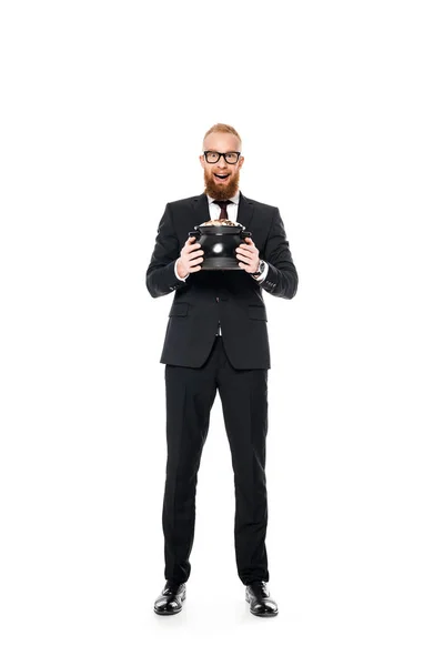 Збуджений бородатий бізнесмен в окулярах тримає горщик з монетами і дивиться на камеру ізольовано на білому — стокове фото