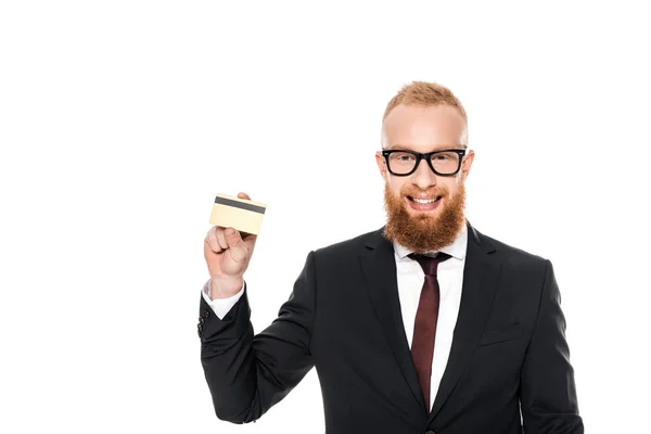 Joven hombre de negocios barbudo en gafas con tarjeta de crédito y sonriendo a la cámara aislado en blanco - foto de stock