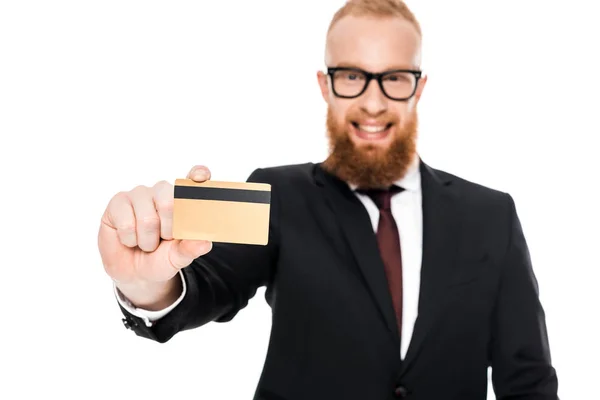 Visão close-up de belo empresário barbudo em óculos segurando cartão de crédito e sorrindo para a câmera isolada em branco — Fotografia de Stock