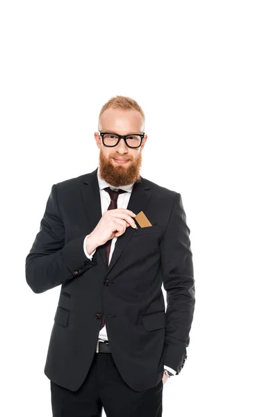 Красивий бородатий бізнесмен в окулярах тримає кредитну картку і посміхається на камеру ізольовано на білому — стокове фото
