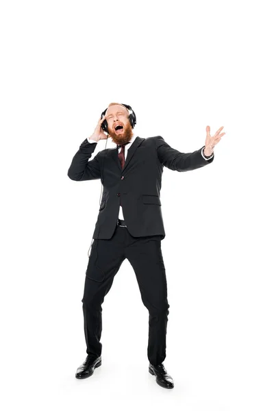 Excited young businessman listening music in headphones isolated on white — Stock Photo