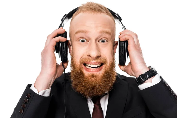 Збуджений молодий бізнесмен в навушниках і посміхається на камеру ізольовані на білому — стокове фото